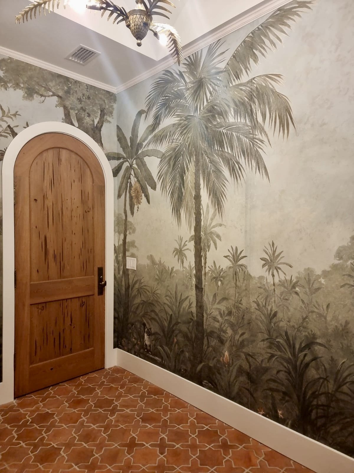 Hand-painted jungle mural powder room with arched door and palm scenery by Kim Delaney, Delaney Fine Finishes