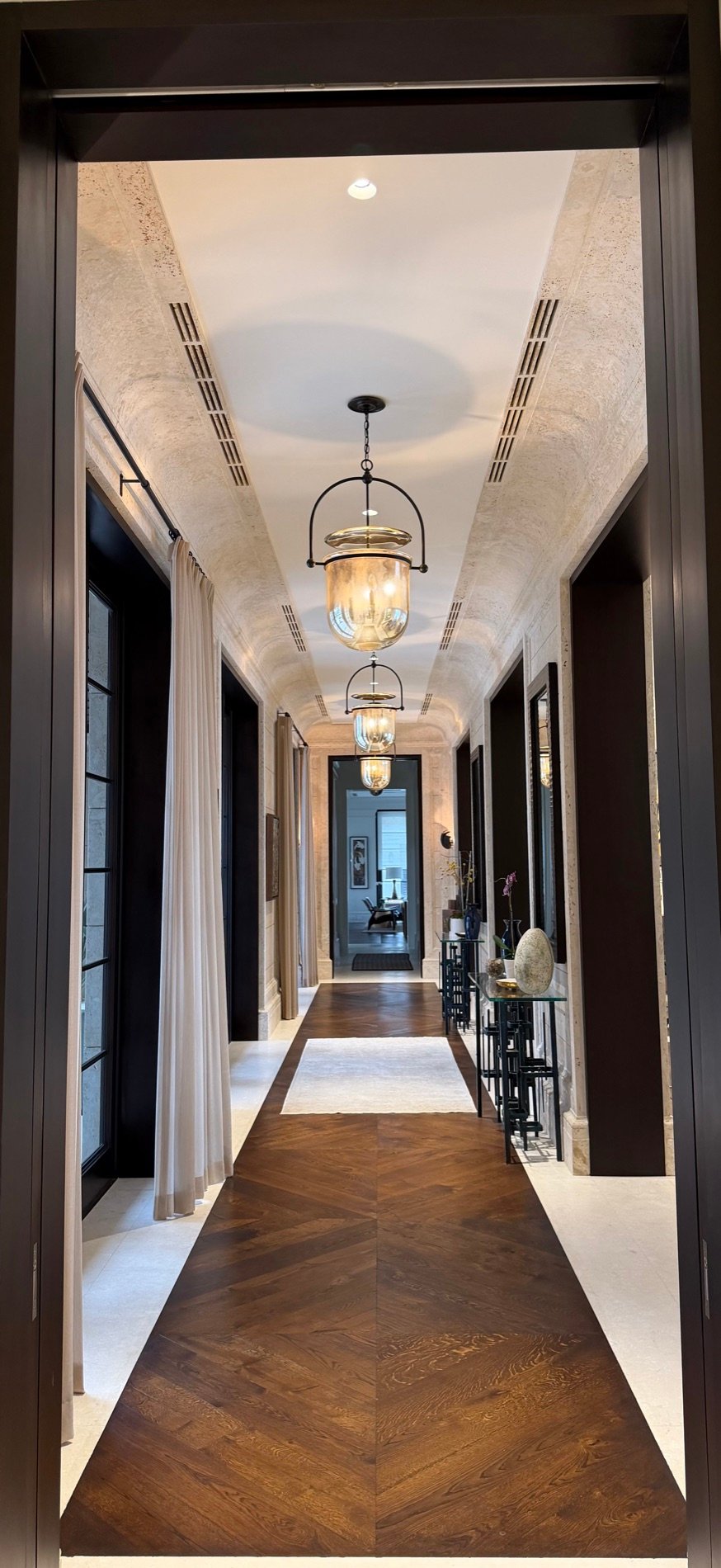 Vaulted travertine-finish hallway with lantern pendants by Kim Delaney, Delaney Fine Finishes