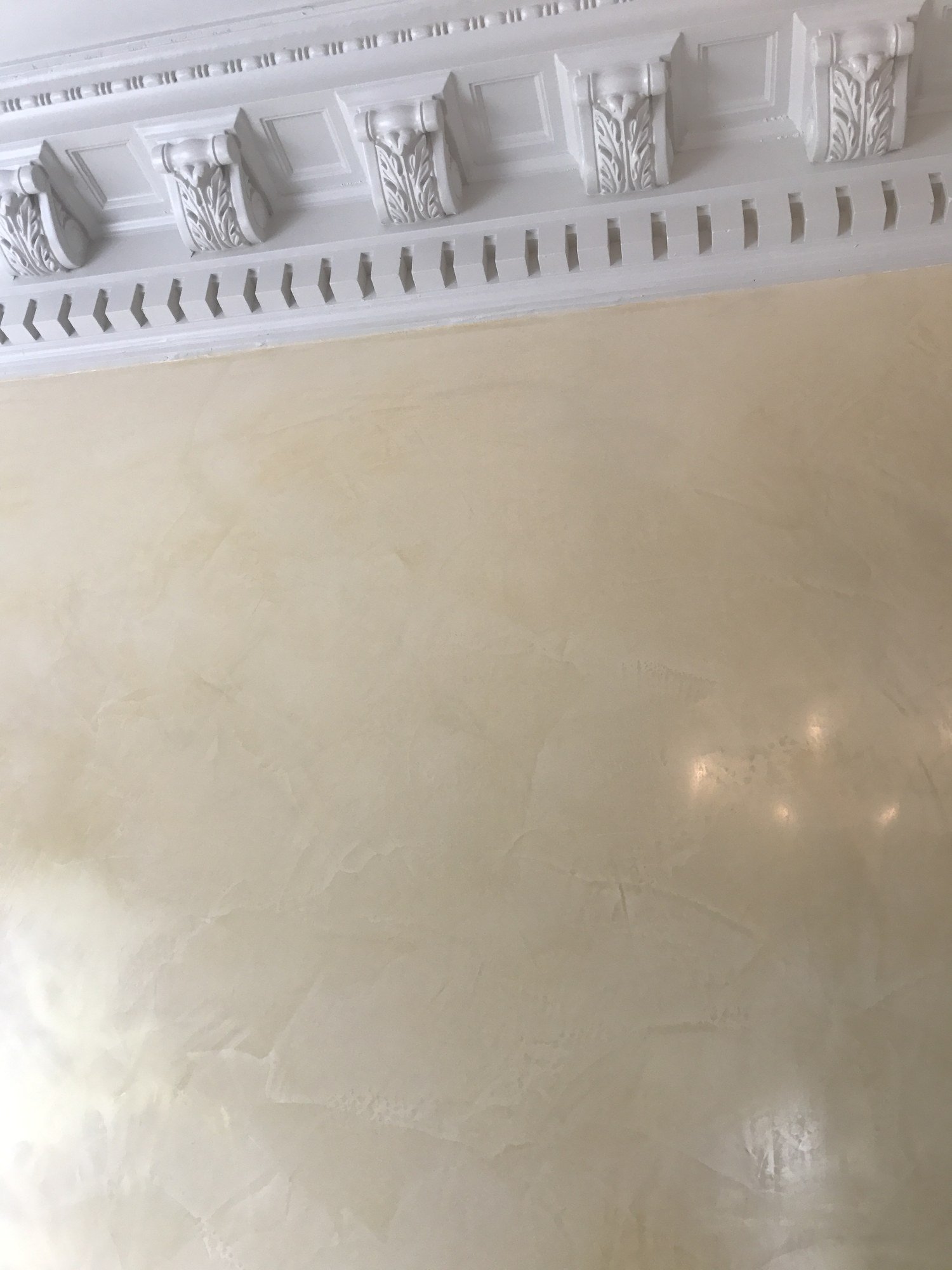 Polished cream Venetian plaster wall beneath a carved cornice by Kim Delaney, Delaney Fine Finishes